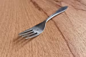 A stainless steel fork placed on a wooden surface